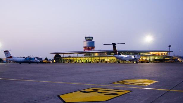 Zwei Flugzeuge stehen auf dem Vorfeld eines Flughafens bei Dämmerung.