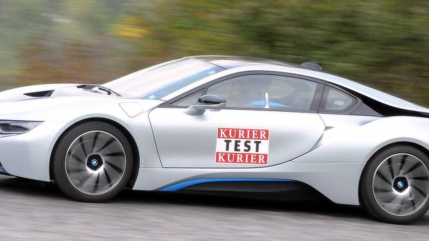 Ein silberner BMW i8 mit dem Aufdruck „Kurier Test Kurier“ fährt auf einer Straße.