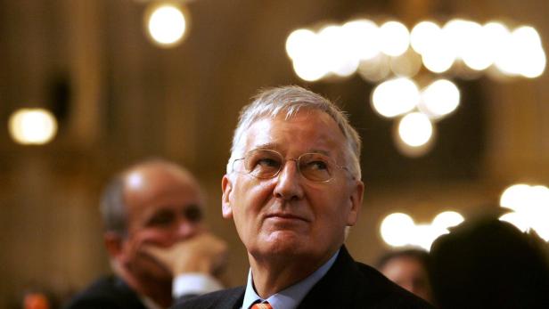 Ein älterer Mann mit Brille blickt in einem Raum mit Lichtern nach oben.