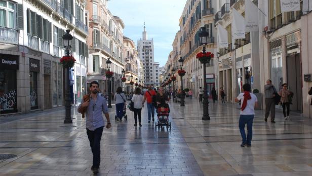 Menschen flanieren auf einer belebten Einkaufsstraße in Málaga, Spanien.