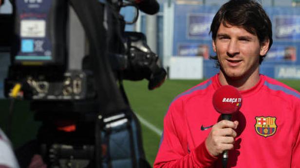 Lionel Messi hält ein Mikrofon von Barça TV in der Hand.