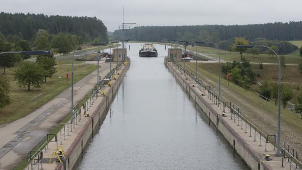 Ein Frachtschiff fährt in eine Schleuse auf einem Kanal ein.