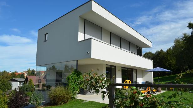 Ein modernes, zweistöckiges Haus mit Garten an einem sonnigen Tag.