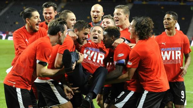 Fußballspieler feiern ihren Trainer, der in die Luft gehoben wird.