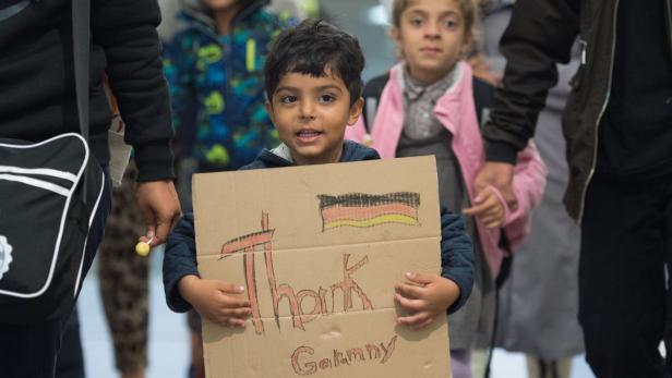 Ein Kind hält ein Pappschild mit der Aufschrift „Thank Germany“ und einer deutschen Flagge.