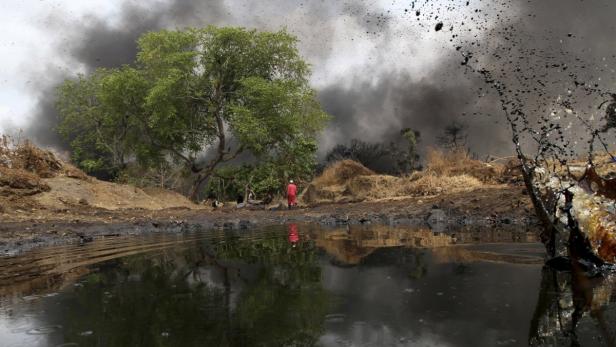 A man walks as crude oil spills from a pipeline in Dadabili, Niger state April 2, 2011. Nigeria postponed parliamentary elections nationwide until Monday after voting materials failed to arrive in many areas, a major blow to hopes of a break with a history of chaotic polls in Africa&#039;s most populous nation. Voting materials also failed to arrive in large parts of the southern oil-producing Niger Delta. REUTERS/Afolabi Sotunde (NIGERIA - Tags: ENVIRONMENT ENERGY IMAGES OF THE DAY)