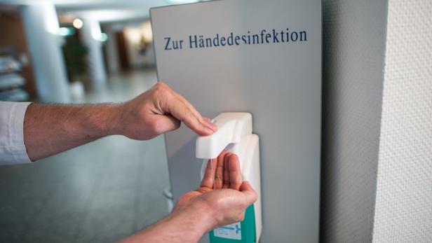Eine Person desinfiziert sich die Hände an einem Spender.