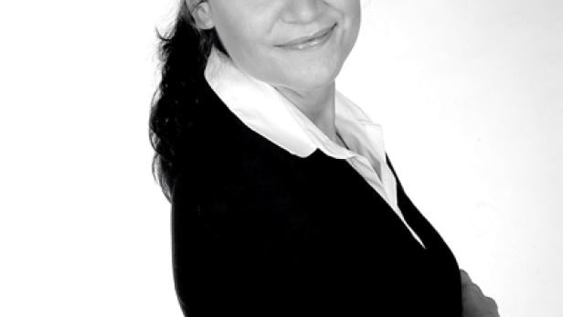 Eine Frau mit verschränkten Armen lächelt in die Kamera.