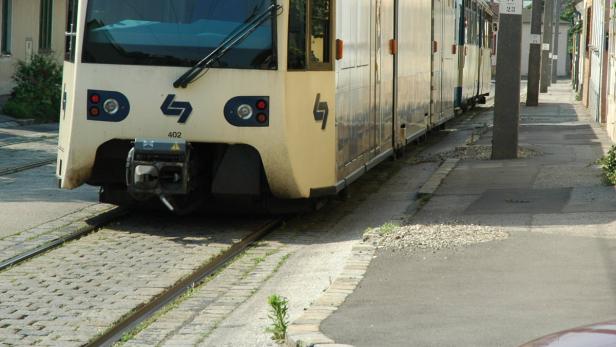 Eine Straßenbahn der Wiener Linien fährt durch eine Wohngegend.