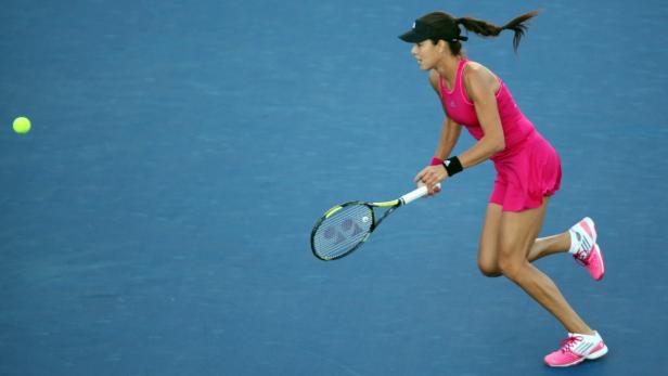 Eine Tennisspielerin in pinkfarbener Sportkleidung schlägt einen Ball.