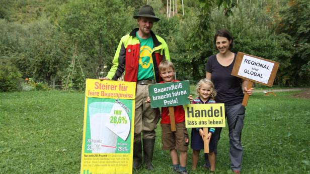 Eine Familie steht auf einer Wiese und demonstriert für faire Bauernpreise.