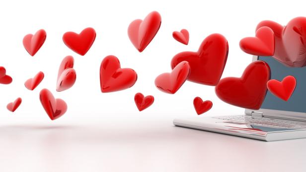 Rote Herzen fliegen von einem Smartphone zu einem Laptop.