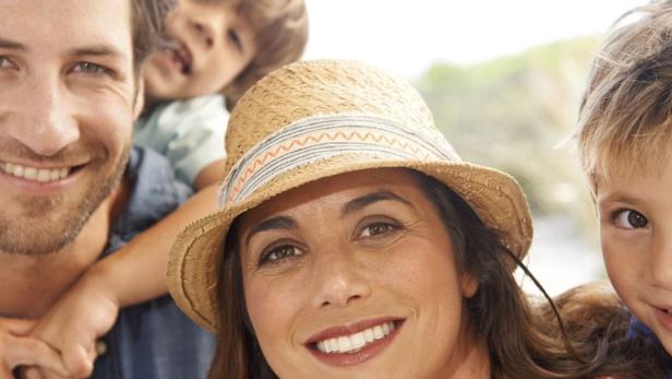Eine lächelnde Familie mit zwei Kindern posiert für ein Foto.