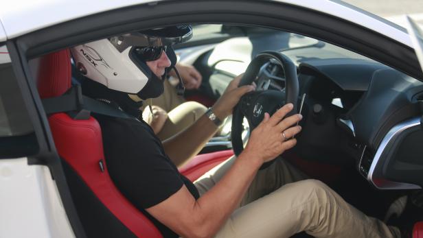 Ein Mann mit Helm sitzt am Steuer eines Honda NSX mit roter Innenausstattung.