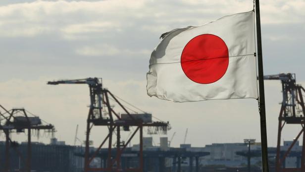 A Japanese flag flutters in front of a shipping container area, at a port in Tokyo December 19, 2012. Japan&#039;s exports fell in November from a year earlier to mark the sixth straight month of declines, a worrying sign that an export recovery may be muted by weak overseas demand - bolstering the case for further monetary stimulus this week. REUTERS/Yuriko Nakao (JAPAN - Tags: MARITIME BUSINESS)