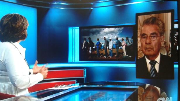 Eine Frau steht in einem CNN-Studio vor einem Bildschirm mit einem Porträt und einer Gruppe von Menschen.