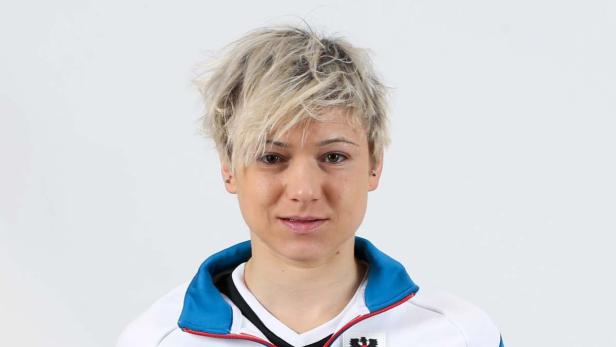 Porträt einer Frau mit blonden, stufigen Haaren vor einem weißen Hintergrund.