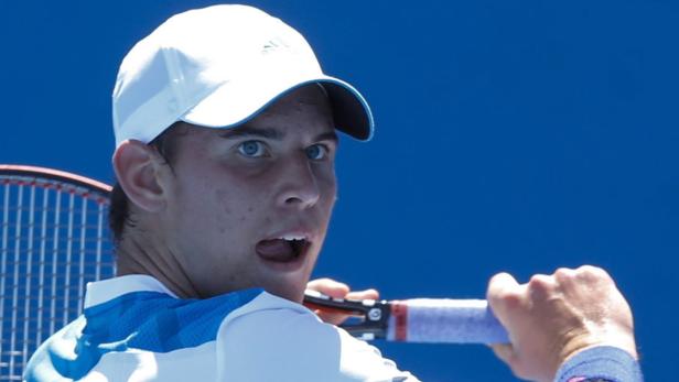 Ein Tennisspieler mit weißer Kappe schlägt einen Ball.