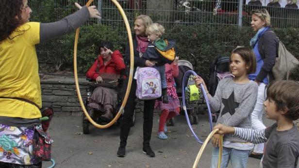 Eine Gruppe von Kindern und Erwachsenen spielt mit Hula-Hoop-Reifen im Freien.
