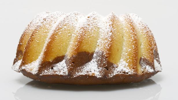 Ein Marmorkuchen mit Puderzucker auf einem weißen Teller.