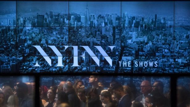 Menschenmenge vor einer Leinwand mit dem Schriftzug „NYFW The Shows“ und einer Skyline von New York.