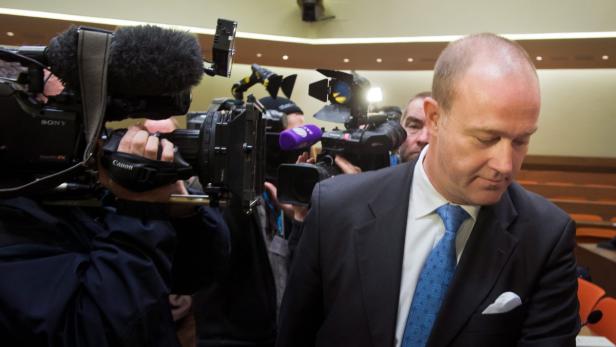 Ein Mann im Anzug wird von einer Gruppe von Kameraleuten umringt.