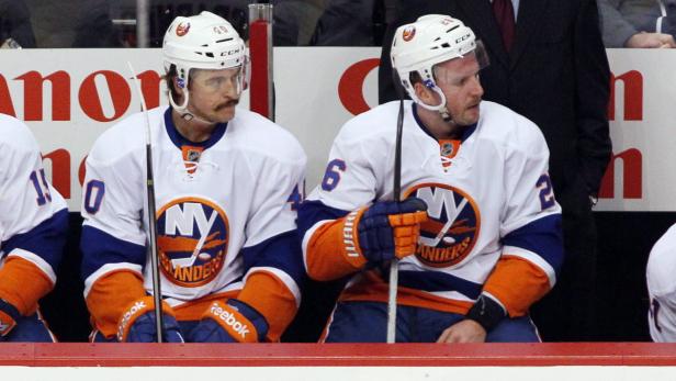 Zwei Eishockeyspieler der New York Islanders sitzen auf der Bank.