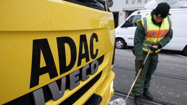Ein gelber ADAC-Abschleppwagen und ein Polizist bei einer Kontrolle.