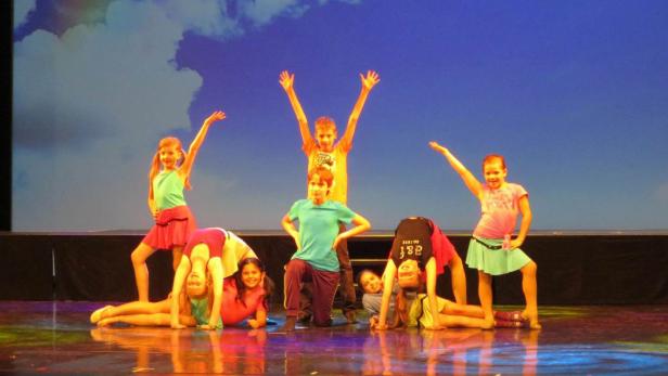 Eine Gruppe Kinder führt eine Tanzroutine auf einer Bühne vor einem Publikum auf.