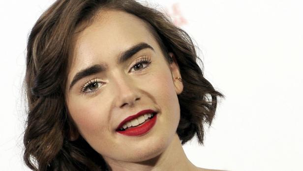 Ein Porträt von Lily Collins mit roten Lippen und braunen, gewellten Haaren.