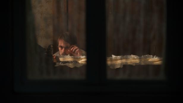 Ein Mann mit Brille schaut durch ein Fenster.