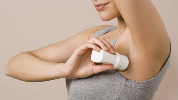Eine Frau benutzt ein Roll-On-Deodorant unter ihrer Achsel.