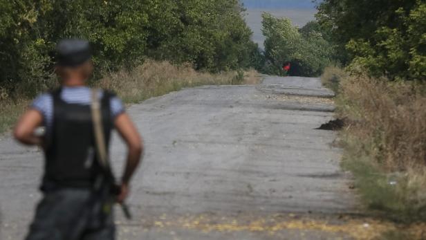 Ein Soldat mit Schutzweste steht auf einer Landstraße.