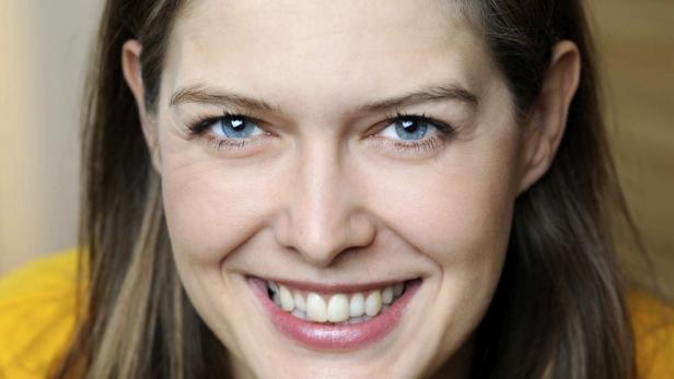 Eine lächelnde Frau mit blauen Augen und braunem Haar.