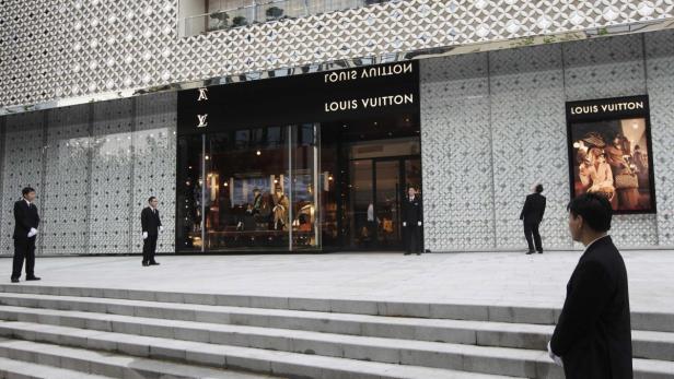 RNPS IMAGES OF THE YEAR 2012 - Security guards stand in front of the soon to be opened largest Louis Vuitton store in China in Shanghai, July 18, 2012. Louis Vuitton is courting China&#039;s wealthy with one-of-a-kind shoes and bags it is branding as unique works of art to reclaim its exclusive cachet in the luxury market. The French luxury brand, a unit of LVMH, is set to open its largest China store in Shanghai on Saturday, complete with a gilded spiral staircase and an invitation-only private floor where big spenders can get their hair done while dreaming up designs for custom bags. REUTERS/Aly Song (CHINA - Tags: BUSINESS)