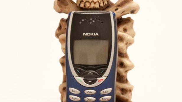 Ein altes Nokia-Handy in einem Ständer aus Knochen und einem Schädel.