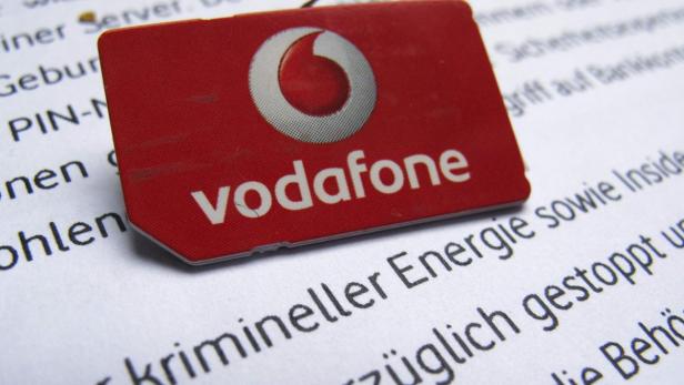 Eine rote Vodafone SIM-Karte liegt auf einem Blatt Papier mit Text.