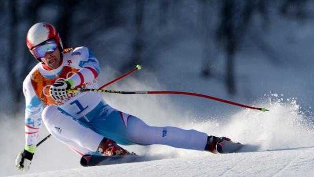 Ein Skirennläufer fährt mit hoher Geschwindigkeit eine schneebedeckte Piste hinunter.