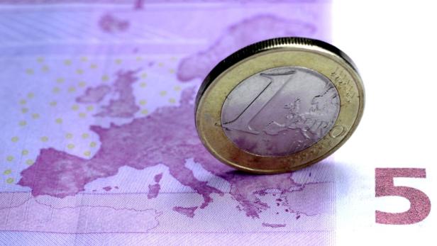 Eine 1-Euro-Münze liegt auf einem violetten 5-Euro-Schein mit einer Europakarte.