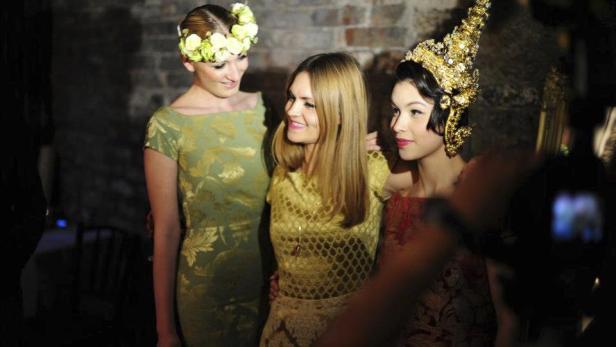 Drei Frauen posieren für ein Foto, eine mit Blumenkranz, eine mit goldenem Kopfschmuck.