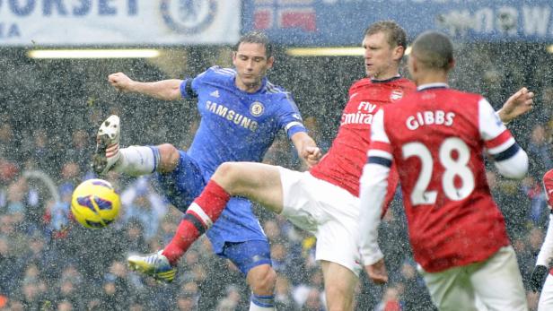 Bei Regen spielen Fußballspieler von Chelsea und Arsenal um den Ball.