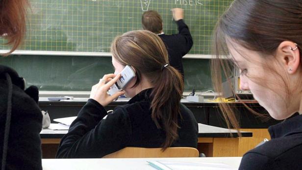 Eine Schülerin telefoniert während des Unterrichts mit dem Handy.