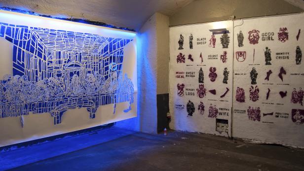 Eine Installation mit einer Darstellung des letzten Abendmahls und Graffiti-ähnlichen Schablonen an den Wänden.