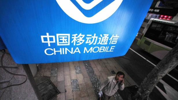 Ein Mann telefoniert unter einem Schild von China Mobile.