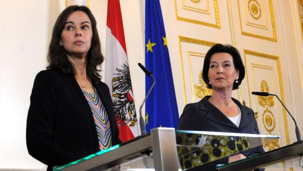 Zwei Frauen stehen an Rednerpulten vor der österreichischen und der EU-Flagge.