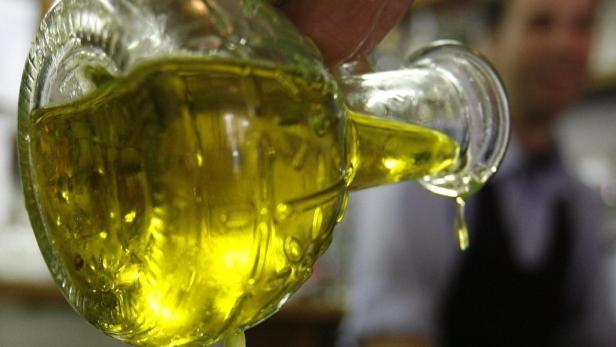 A diner pours olive oil on a salad at a restaurant in Rome May 17, 2007. When you buy a bottle of olive oil, the rolling Tuscan hills on the label and the &quot;made in Italy&quot; stamp should reassure you the product is as Italian as Chianti or Armani. In fact, there is no guarantee the oil is from Italy. That would change under a bill that forces manufacturers to declare where their oil comes from, meaning many famous brands would have to reveal, for the first time, that most of their &quot;Italian&quot; oil is actually from places like Spain and Tunisia. To match feature ITALY-OLIVES/ REUTERS/Dario Pignatelli (ITALY)