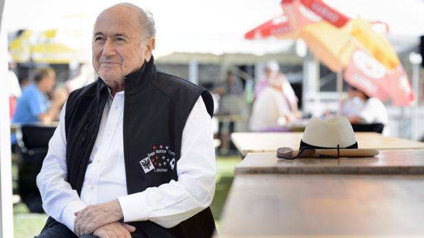 Sepp Blatter sitzt im Freien an einem Tisch.