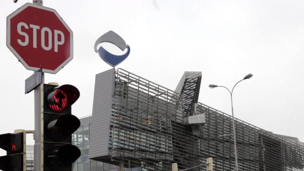 Ein Stoppschild und eine rote Ampel vor einem modernen Bürogebäude.