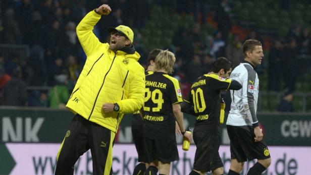 Jürgen Klopp jubelt mit erhobener Faust, umgeben von Spielern von Borussia Dortmund.