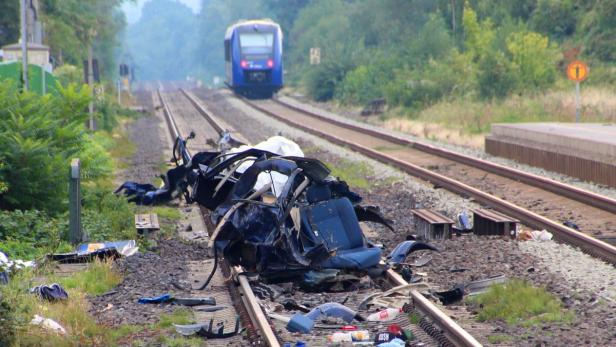 Ein Zug nähert sich einem völlig zerstörten Auto auf den Gleisen.